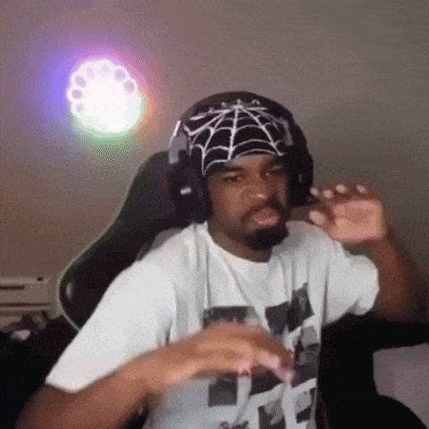 a man wearing headphones and a bandana with a spider web on it is sitting in a chair .