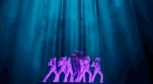 a group of people standing in front of a blue curtain with purple lights behind them