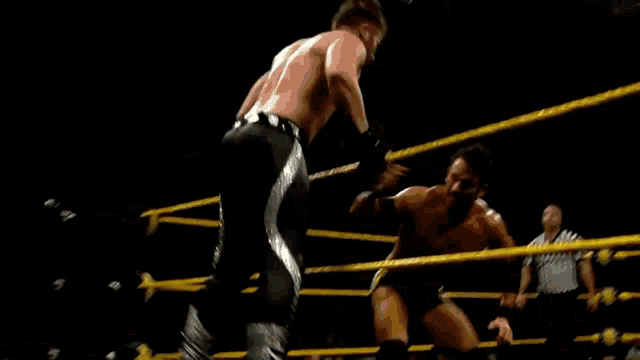 two men are wrestling in a ring with the letter w on the wall