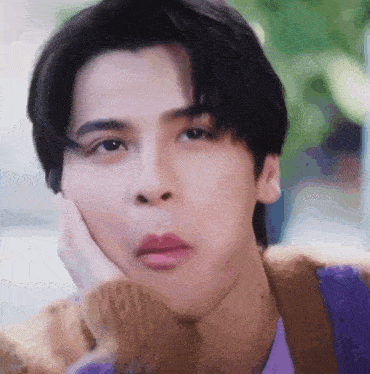 a close up of a young man 's face with his hand on his face