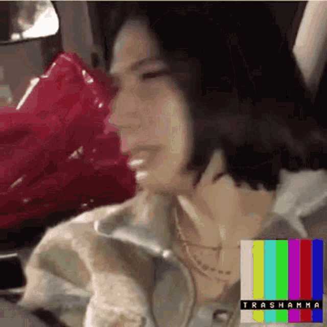 a woman is sitting in the back seat of a car talking on a cell phone and crying .
