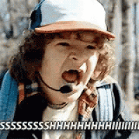 a little boy wearing a hat and a microphone is screaming .