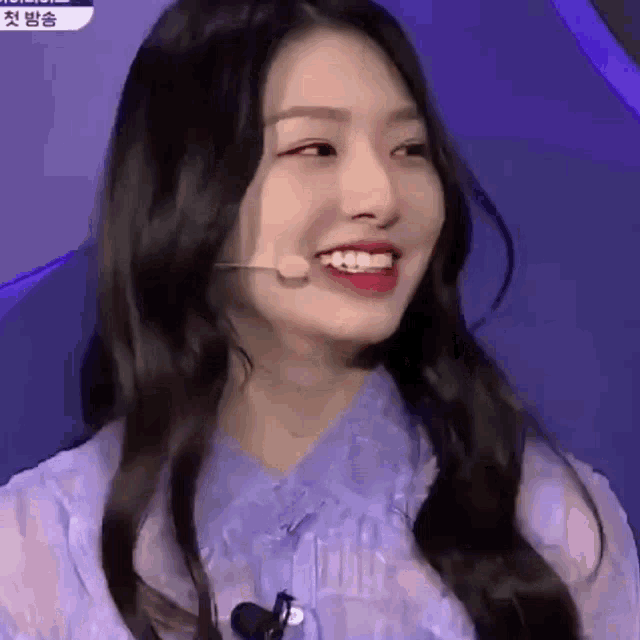 a close up of a girl with long hair wearing a microphone and smiling .