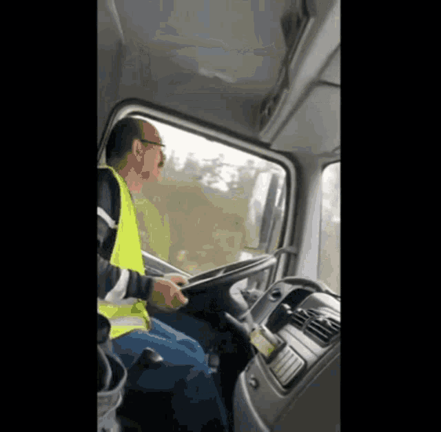 a man wearing a yellow vest driving a truck