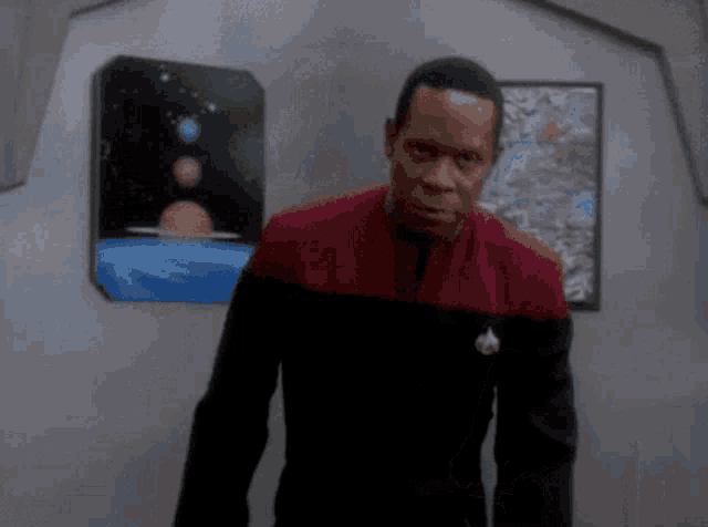 a man in a red jacket is standing in front of a painting of planets