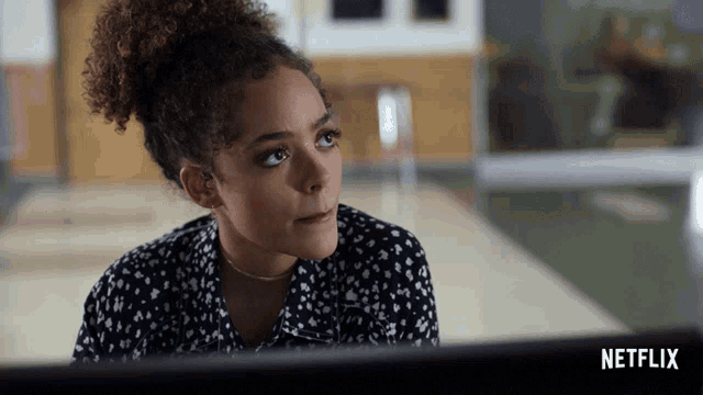a woman sitting in front of a computer with a netflix logo in the background