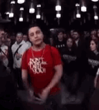 a man in a red shirt is talking to another man in a crowd of people .