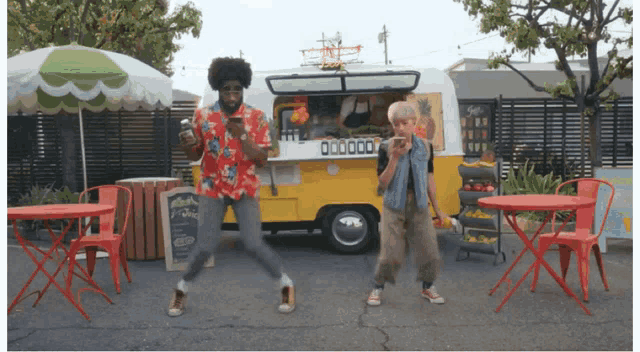 a man and a boy are dancing in front of a food truck