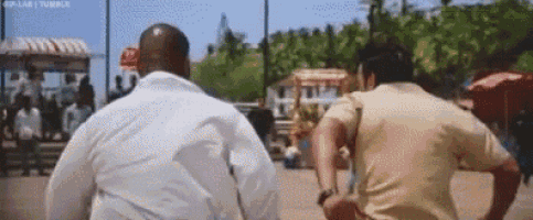two men are running down a street holding hands and looking at each other .