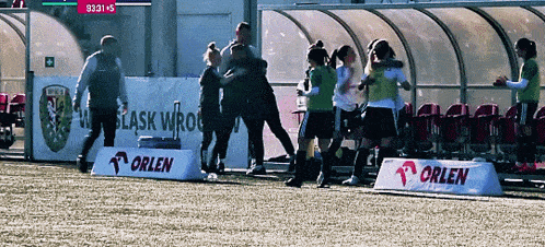 a group of soccer players are hugging in front of an orlen banner