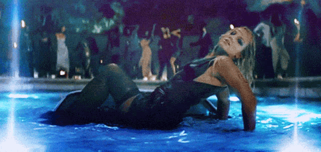 a woman in a black dress is laying in the water