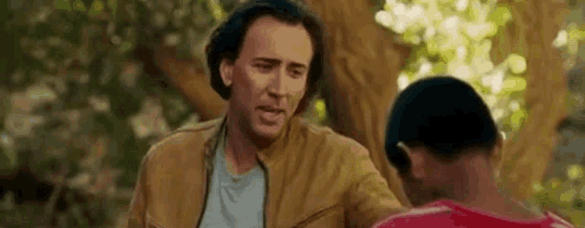 a man in a brown jacket is talking to a young boy .