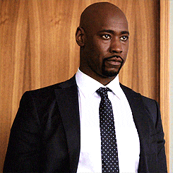a man in a suit and tie is standing in front of a wooden wall