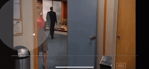 a man in a suit is walking through a door that says ' amc ' on it