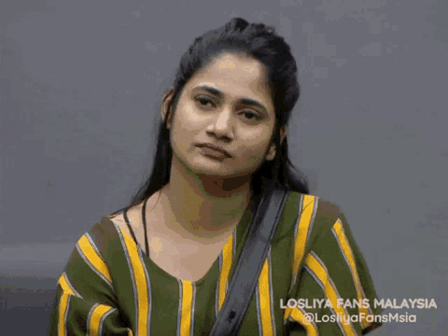 a woman wearing a green and yellow striped shirt with the words losliya fans malaysia on the bottom right