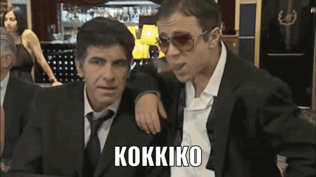 a man smoking a cigar next to another man with the word kokkiko written on the bottom