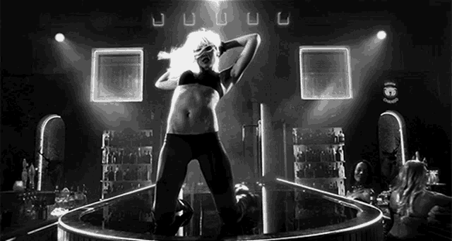a woman in a bikini is dancing on a stage in a black and white photo