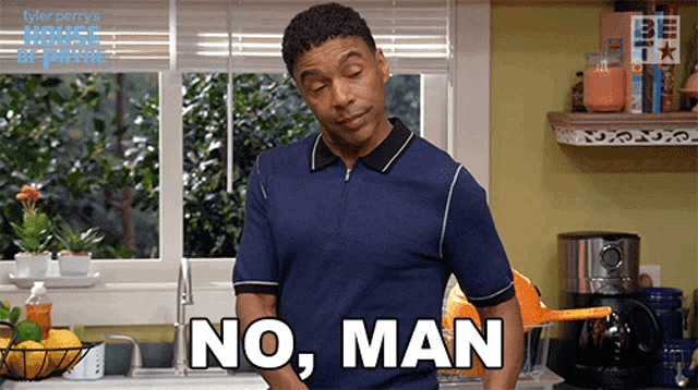 a man in a blue shirt is standing in a kitchen and says no man