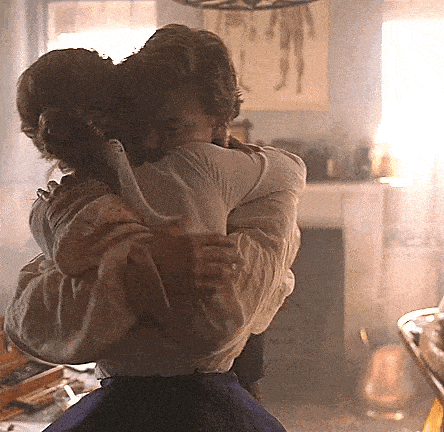 a man and woman are hugging in a living room .