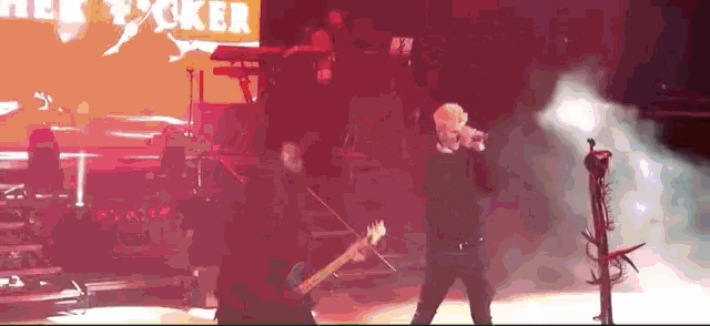 a man sings into a microphone while playing a violin on stage