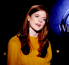 a woman in a yellow top stands in front of a sign that says w.i.