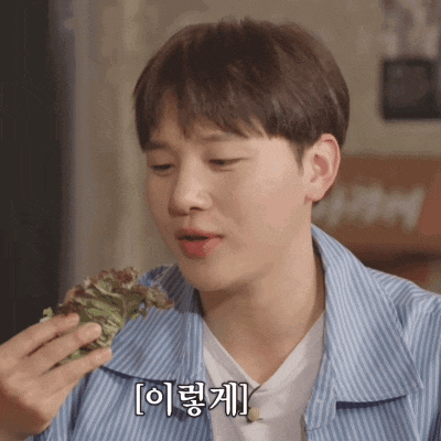 a man in a blue striped shirt is eating lettuce