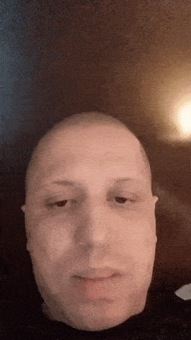 a close up of a man 's face with a shaved head .