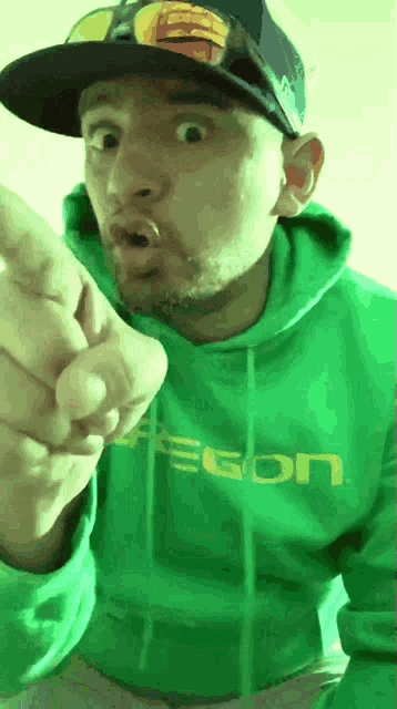 a man wearing a green egon hoodie and hat