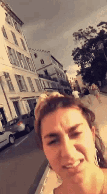 a woman is making a funny face in front of a building