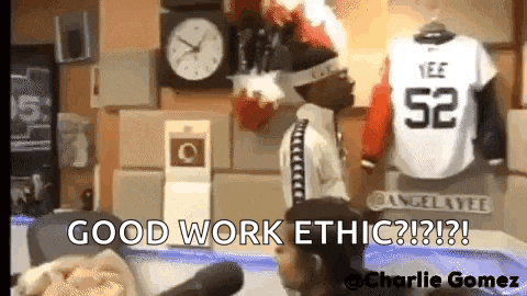 a man is standing in front of a clock and a jersey that says ' good work ethic ' on it .