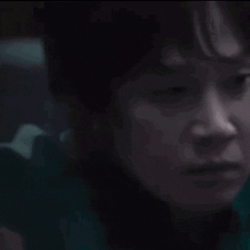 a close up of a person 's face in a dark room with a blurred background .