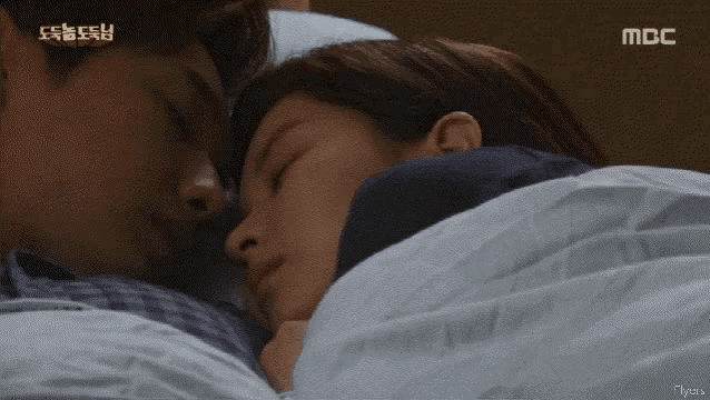 a man and a woman are sleeping in a bed with mbc written on the bottom