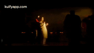 a group of people are standing in a dark room .