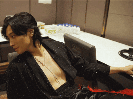 a shirtless man sits in a chair with his arm resting on a desk