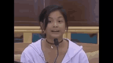 a young woman is sitting in front of a microphone and making a face .