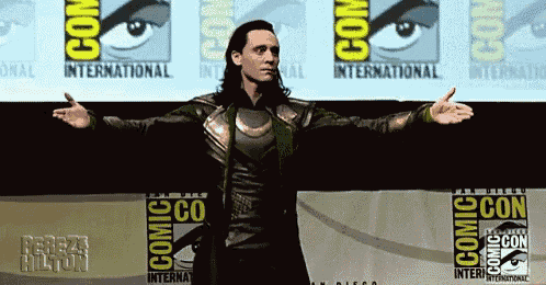 a man is standing in front of a comic con banner