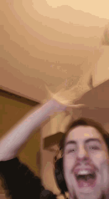 a man wearing headphones is making a funny face while pointing at the ceiling .