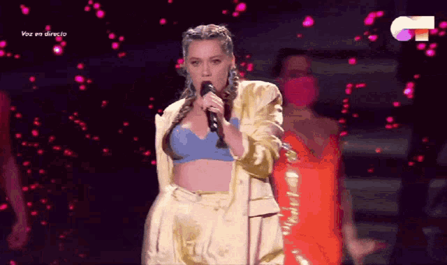 a woman singing into a microphone with the words voz en directo on the bottom right