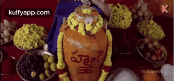 a large clay pot is sitting on top of a table surrounded by bowls of food .