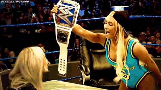 a woman in a wrestling ring holds a championship belt
