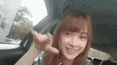 a young woman is sitting in a car making a funny face .