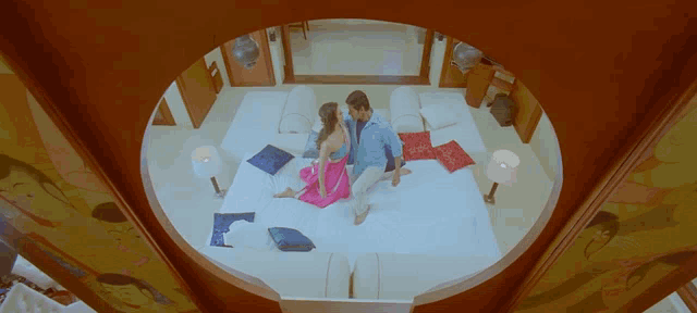 a man and a woman laying on a bed in a room