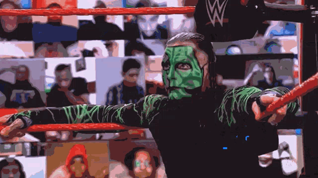 a wrestler with green paint on his face holds a red rope