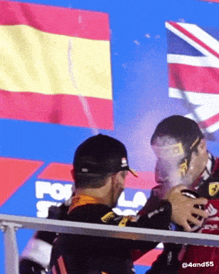a man is spraying another man 's face with champagne in front of a fox logo