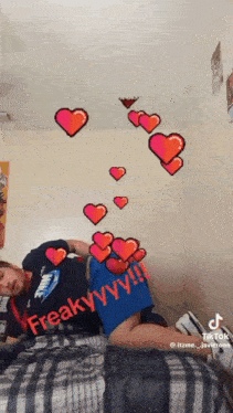 a person is laying on a bed with hearts coming out of their pants .