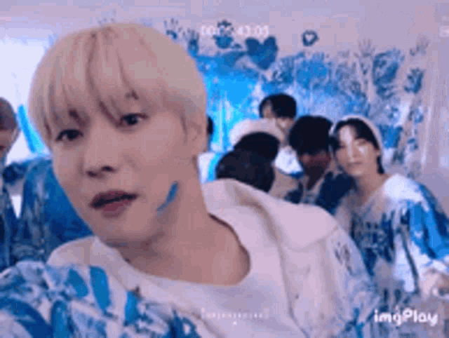 a man with blue paint on his face is taking a selfie with a group of people behind him .