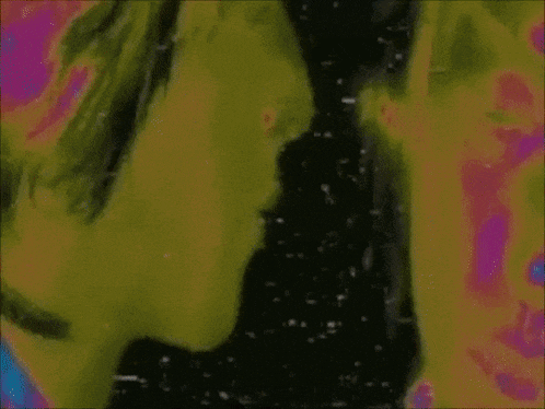 two people are standing next to each other in front of a wall