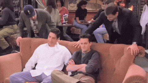 a group of men are sitting on a couch in a restaurant with a sign that says ' coca cola ' on it