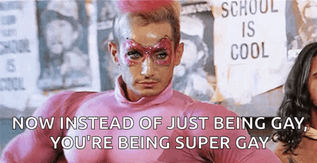 a man in a pink superhero costume is standing in front of a sign that says school is cool .
