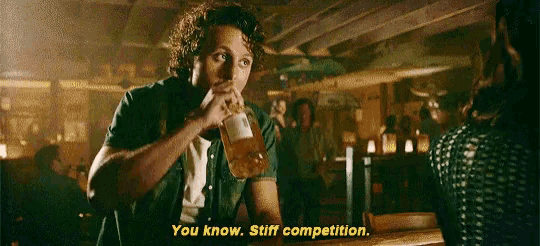a man is sitting at a bar drinking a beer and saying " you know stiff competition " .